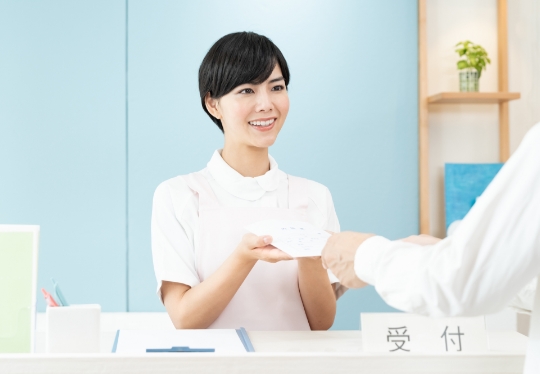 受付で退院手続きと支払いを行う様子